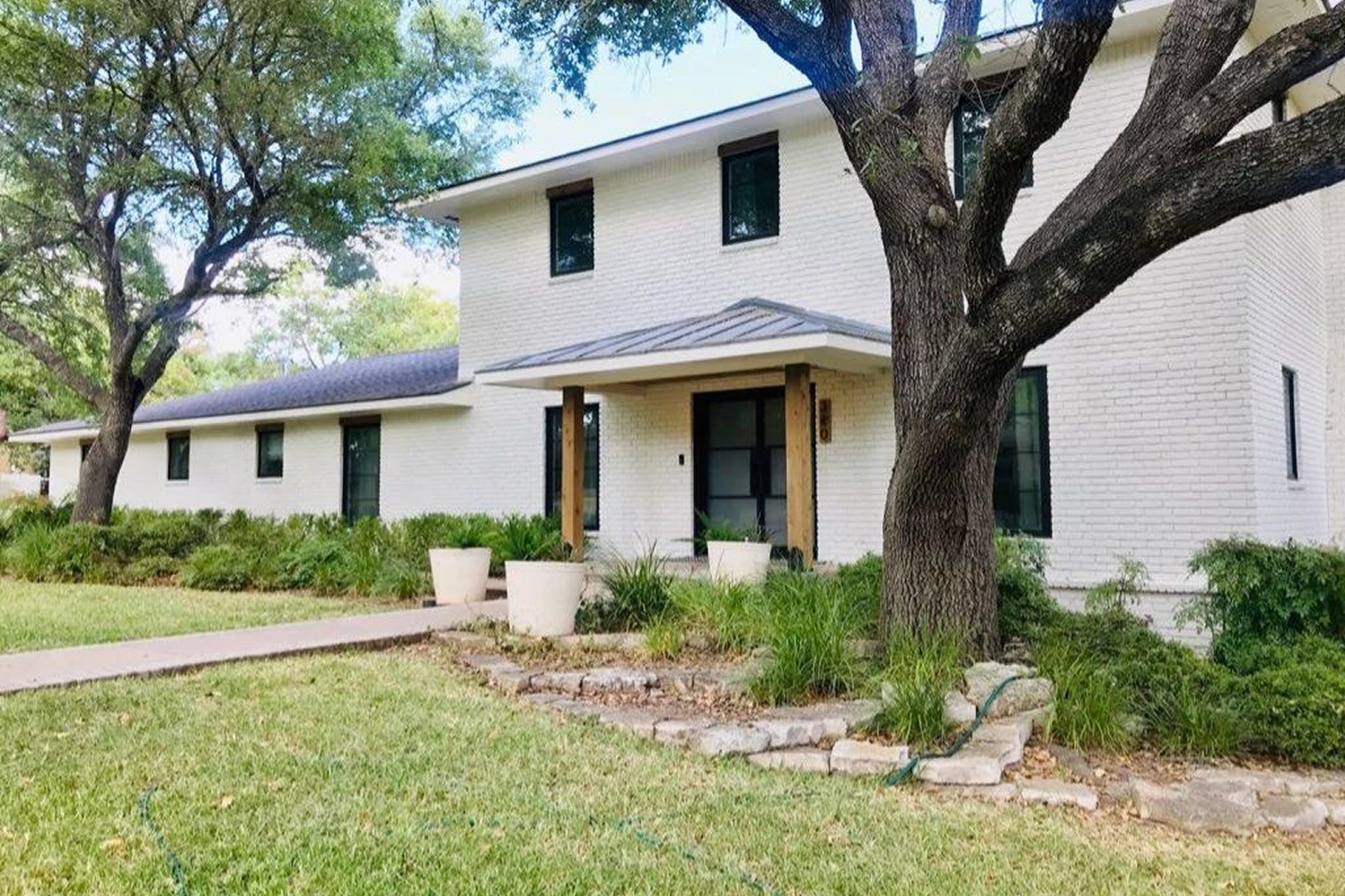 External view of a white stucco home from the front, showcasing the black replacement windows.