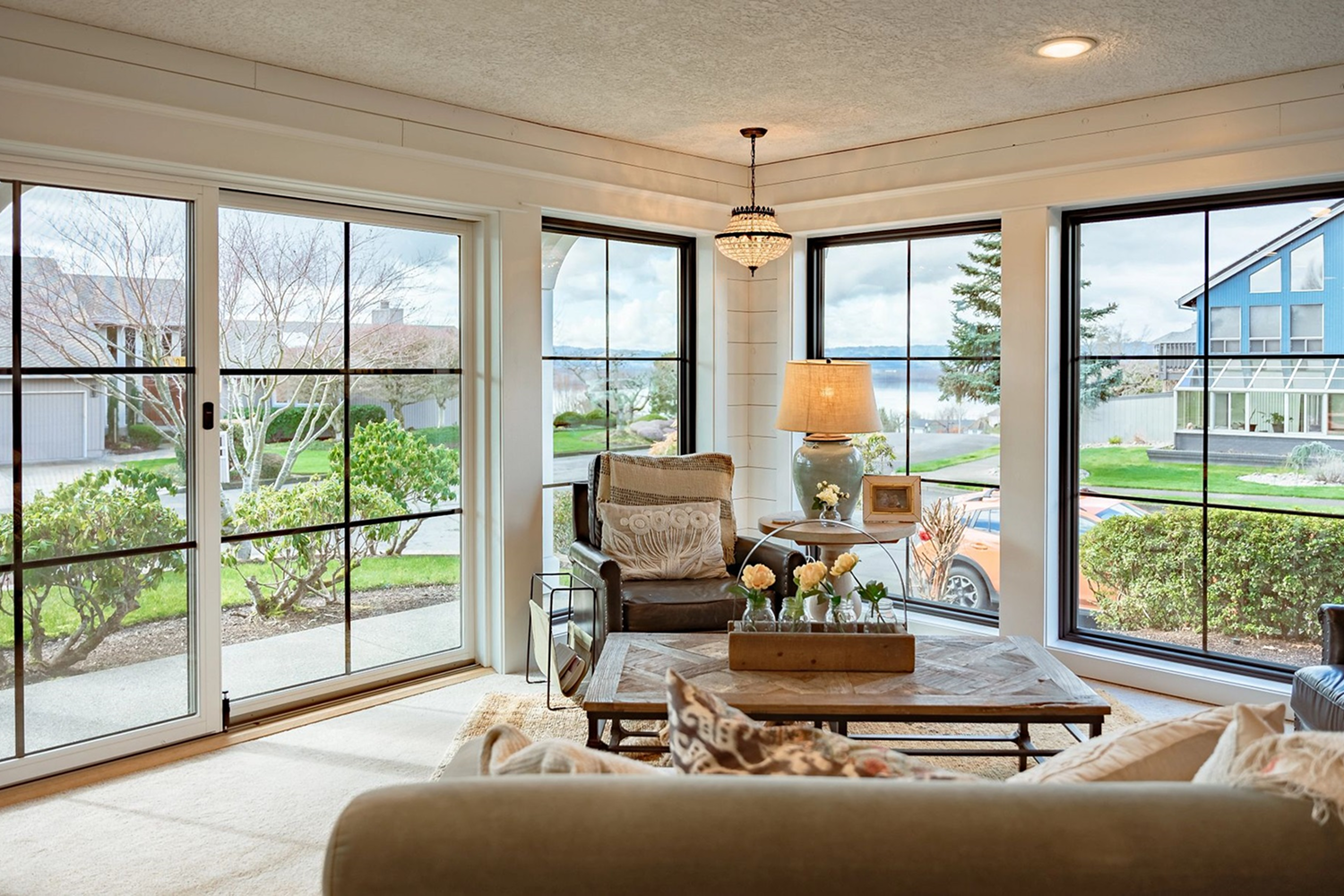 Lounge room warmly lit with large picture windows across the two exterior walls.