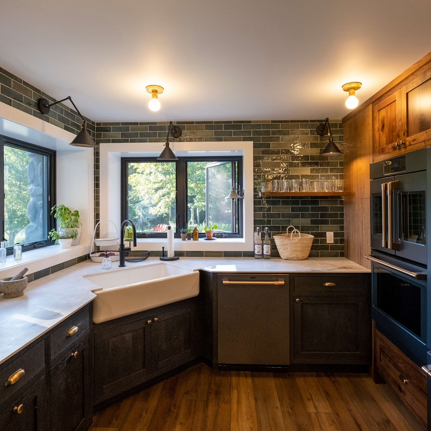 Subway tile kitchen with wood floors, black cupboards, and black casement windows above the sink.