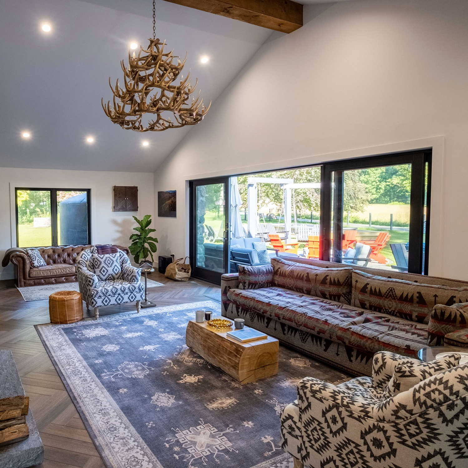 High ceiling living room with large black picture windows and casement windows.
