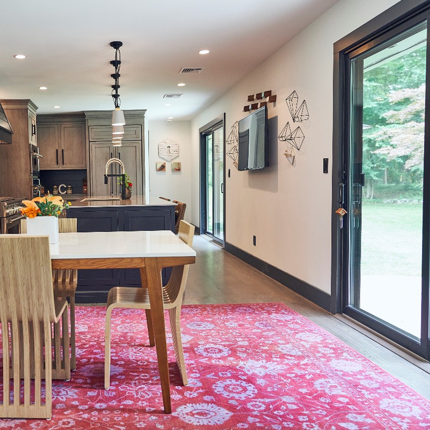 Kitchen with a magenta rug on the floor in front of a black sliding door.