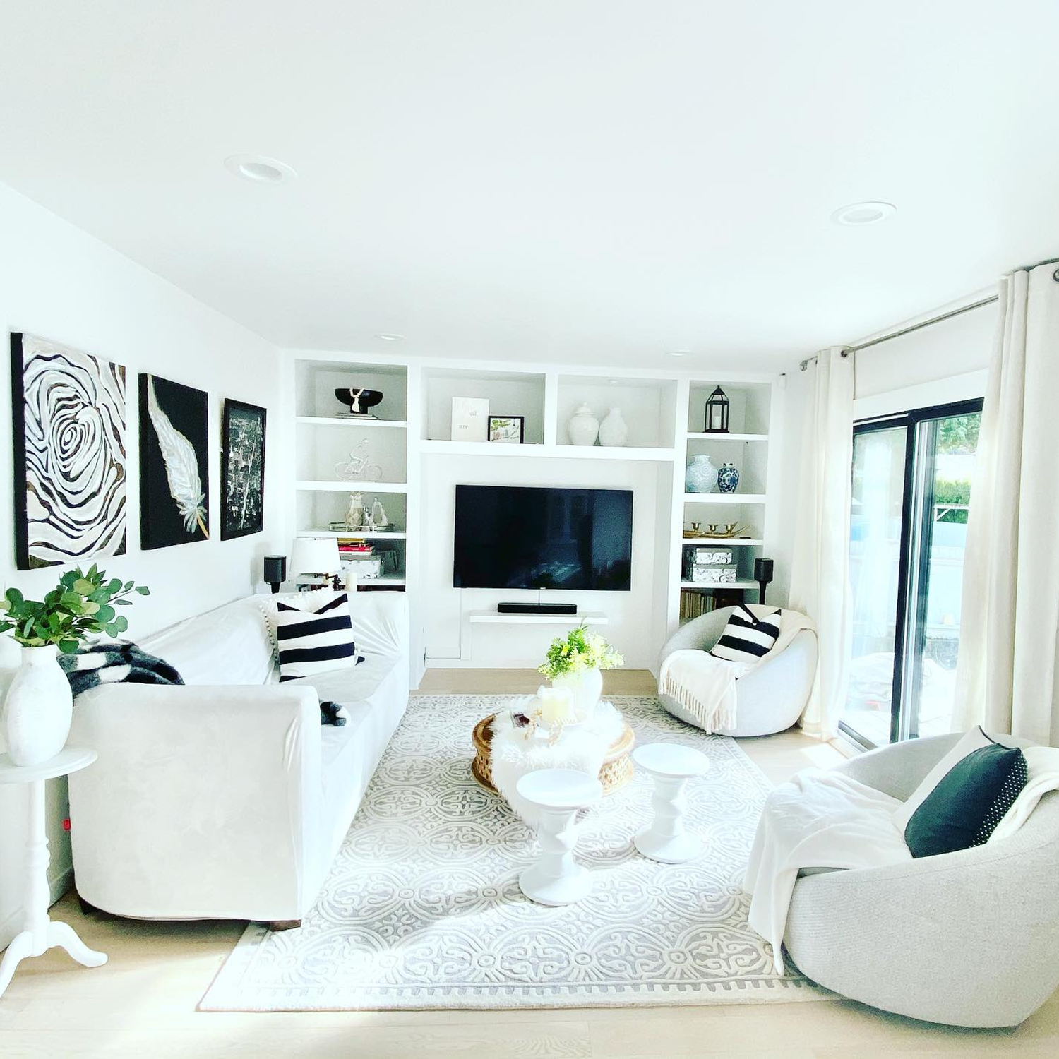 White living room with white walls and white furniture with natural light coming in through a sliding patio door