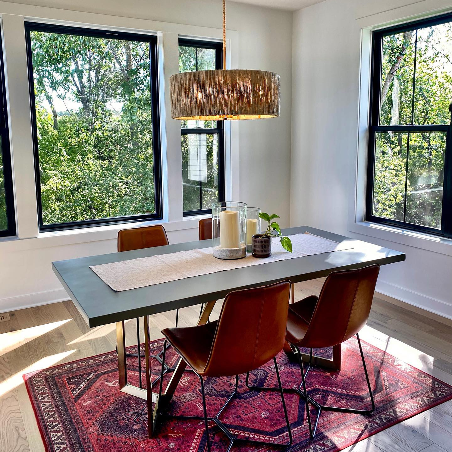 Modern design dining area with large black picture and double hung windows all around.