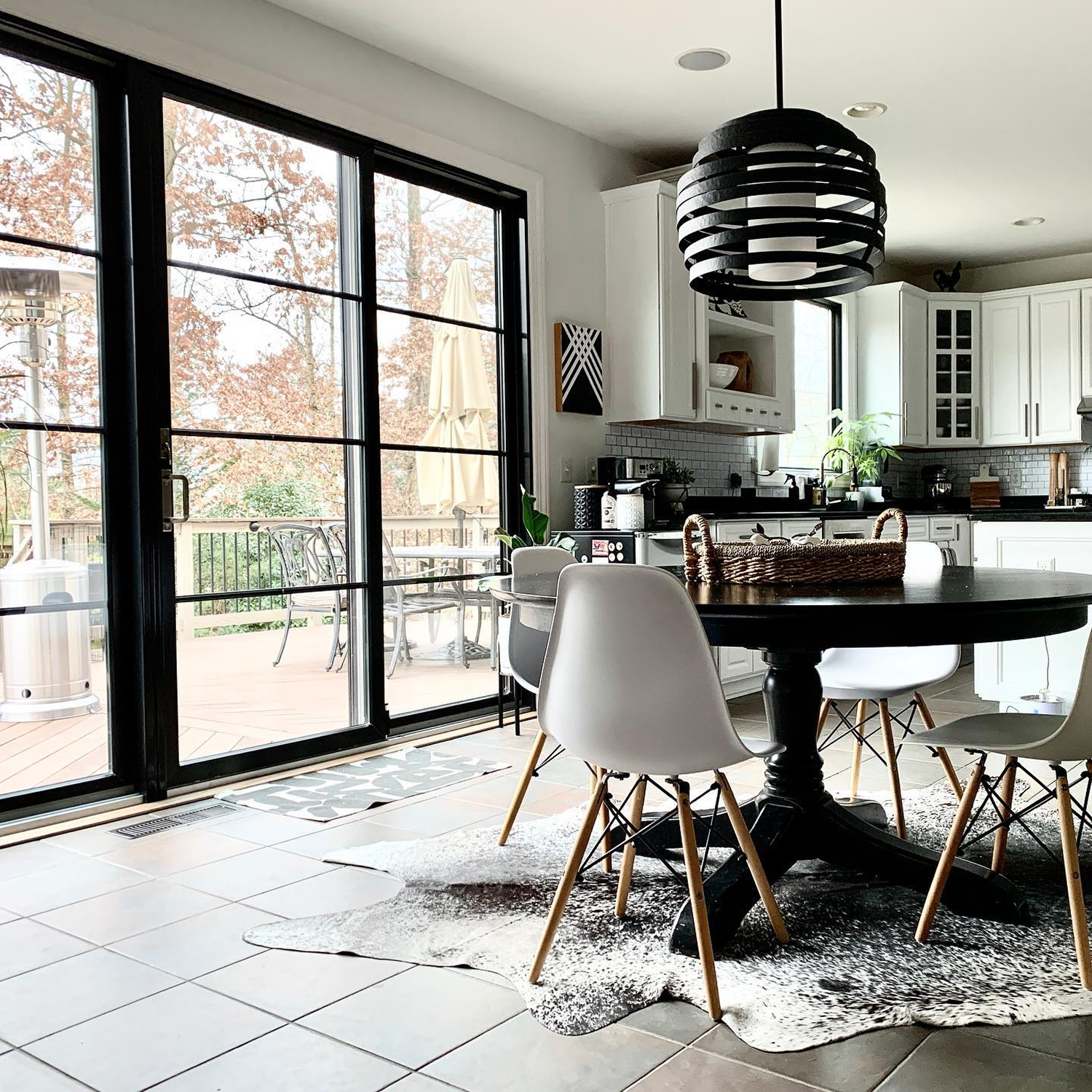 White modern kitchen naturally lit by two sets of black sliding patio doors.