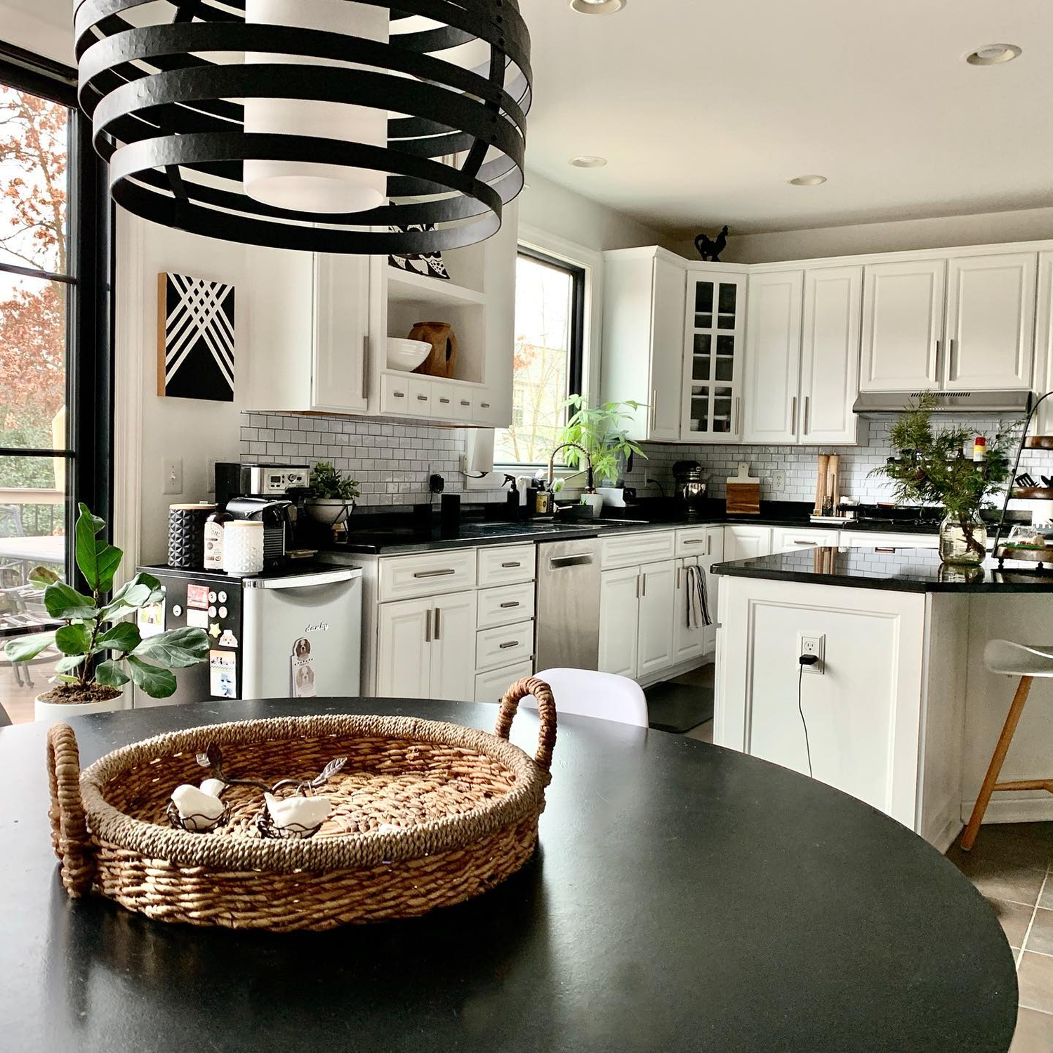 Kitchen with wood floors and white cabinets with a black patio door and black window above the sink.