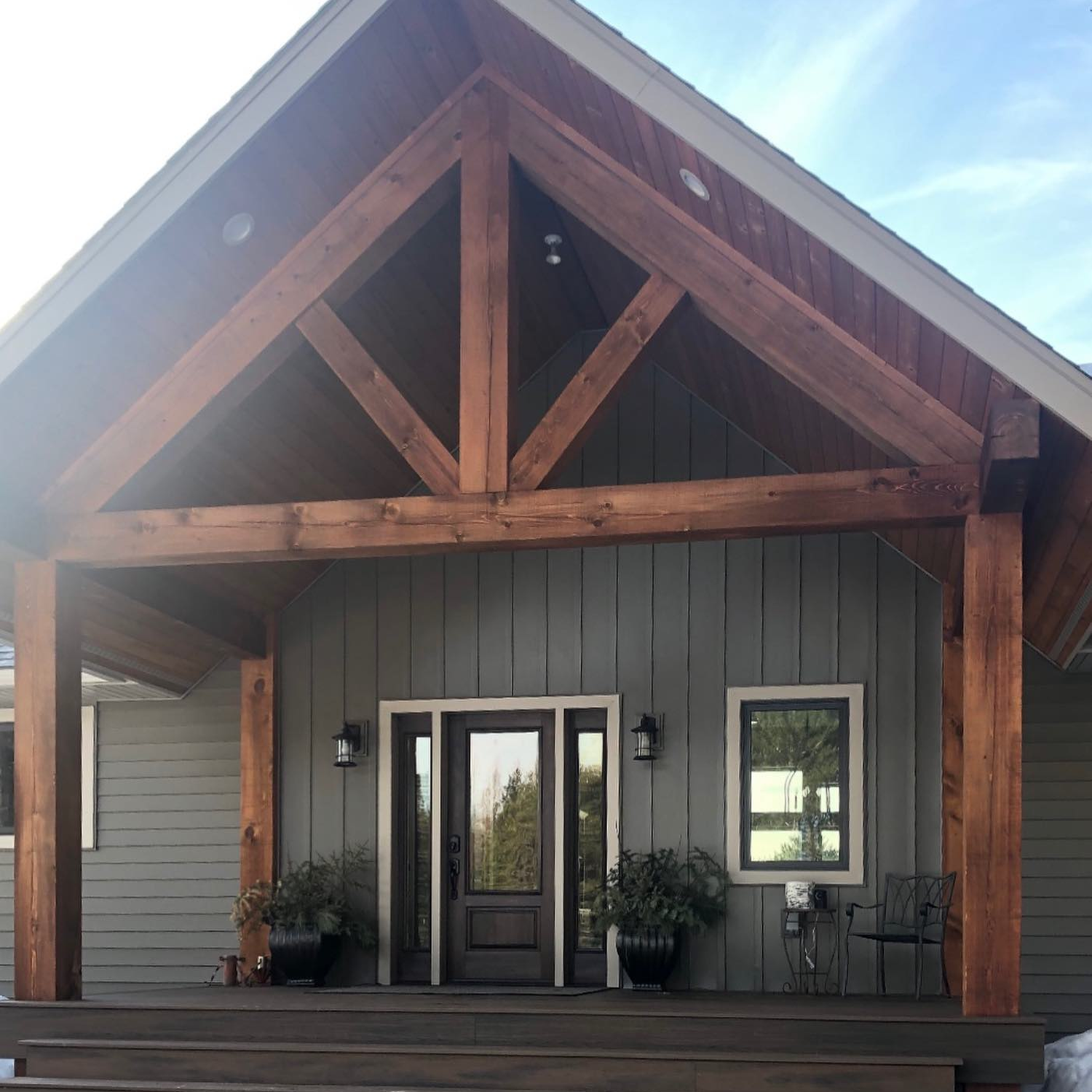 Beautiful wooden A-frame home with a black ensemble from door and black windows.