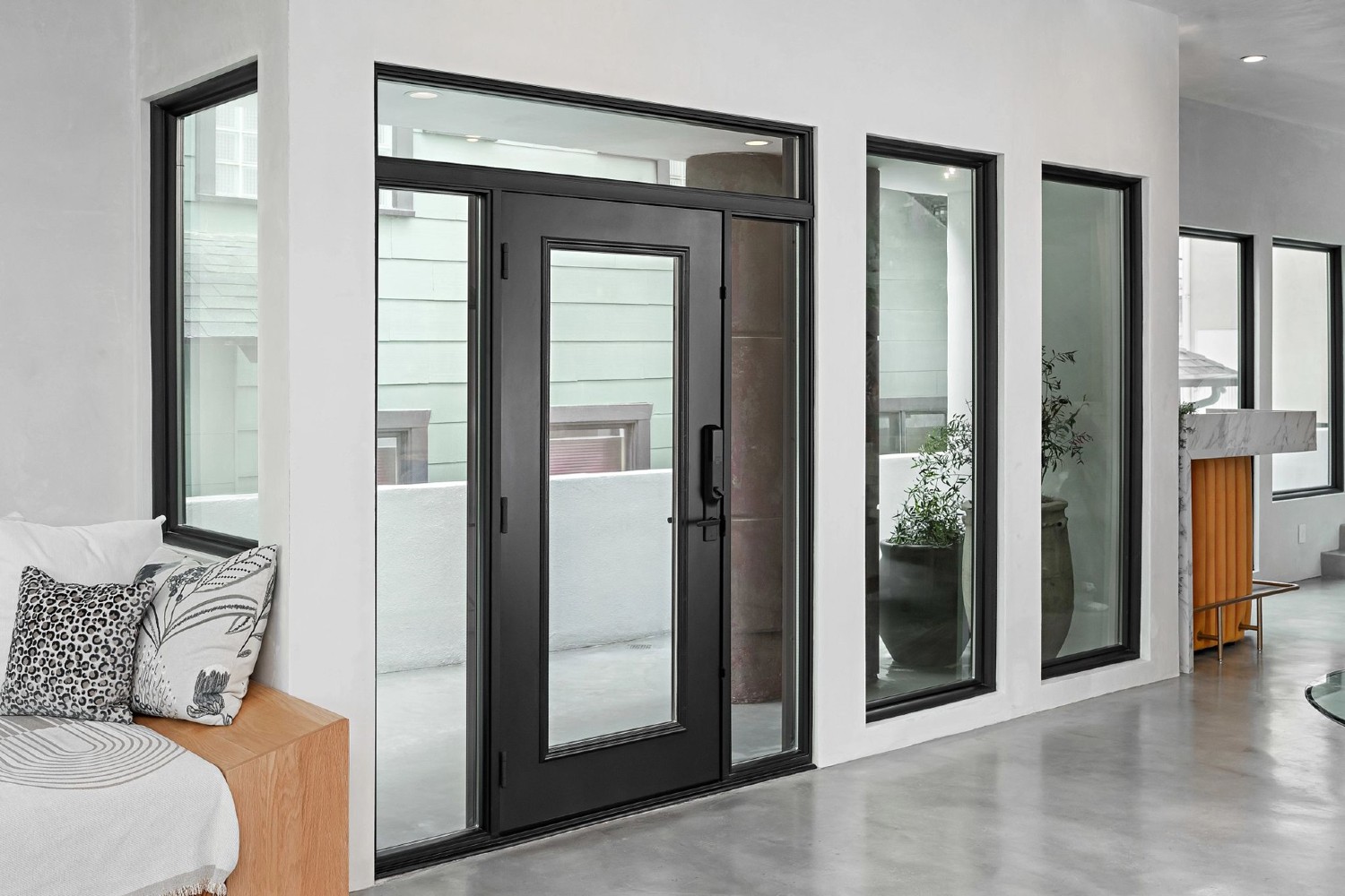 The Radiant Collection Designer Door at Breegan Jane's house. It is a black door with much glass. It has sidelights and a transom. 