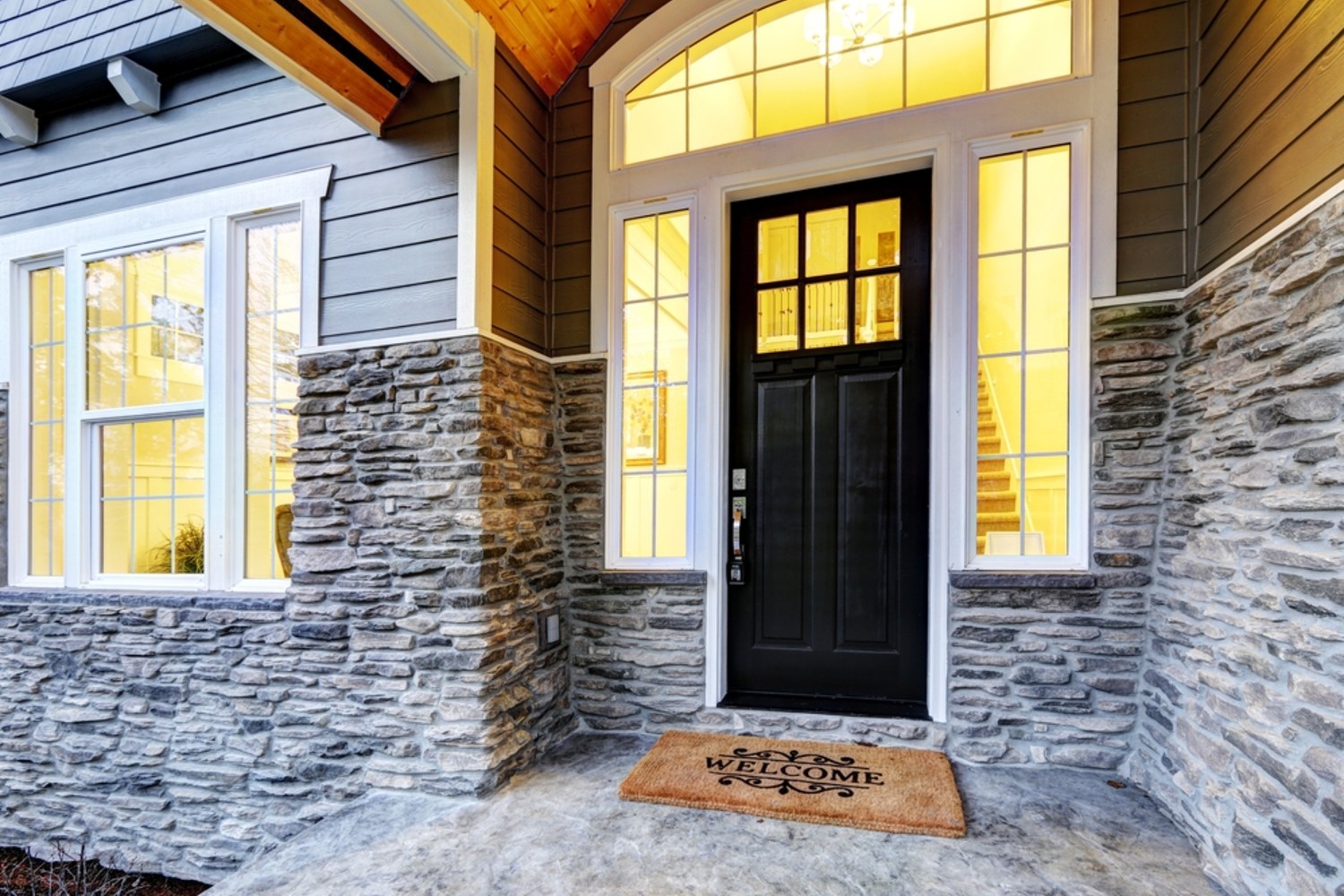 Black door with stack stone siding half way up and brown siding the rest of the way.