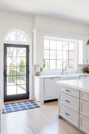 The arched manor has an all white kitchen and a black door with grilles.
