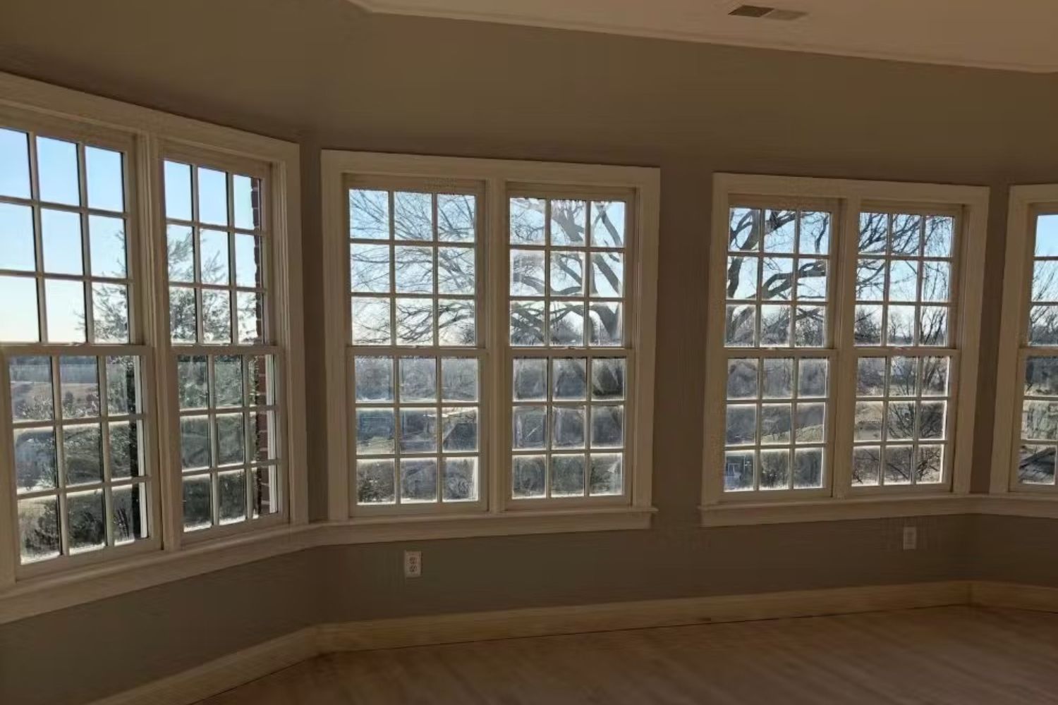 Bedroom before remodel. Dark tan walls and old double hung windows.