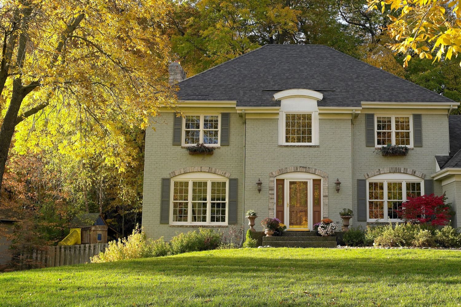 Large light green home with white Renewal by Andersen windows