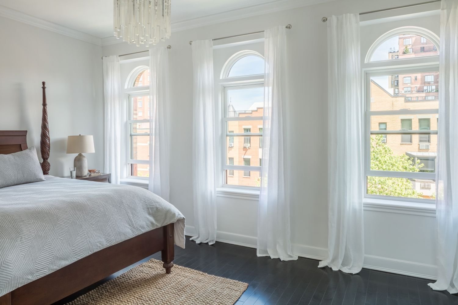 White double hung windows by Renewal by Andersen in a all white room with a giant bed and drapes