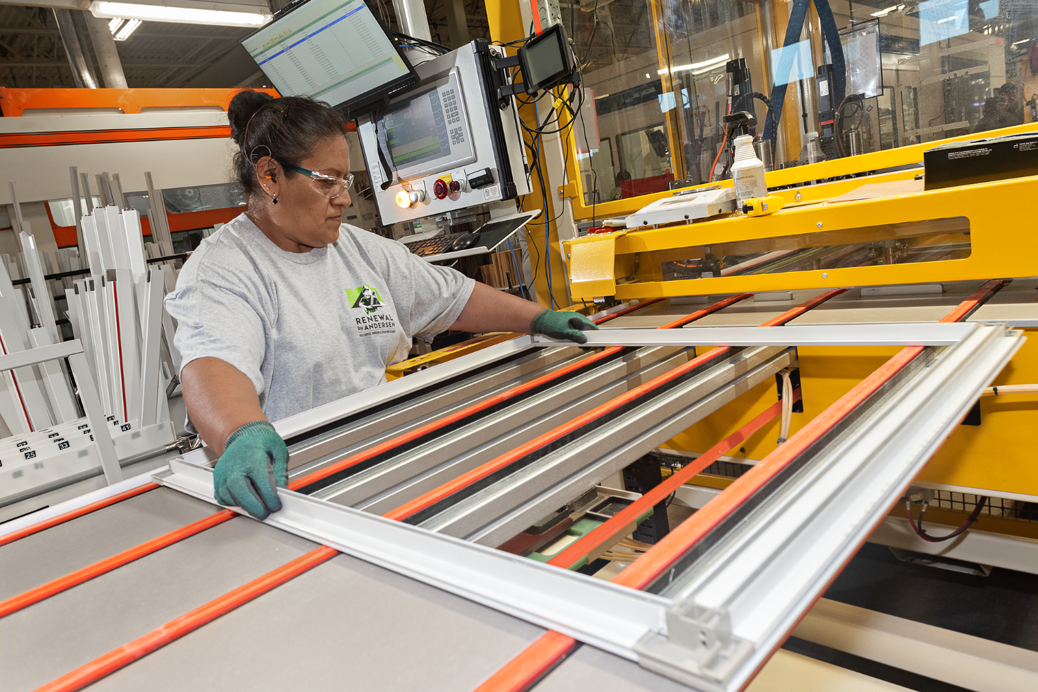 Person creating a window frame at a Renewal by Andersen manufacturing facility.