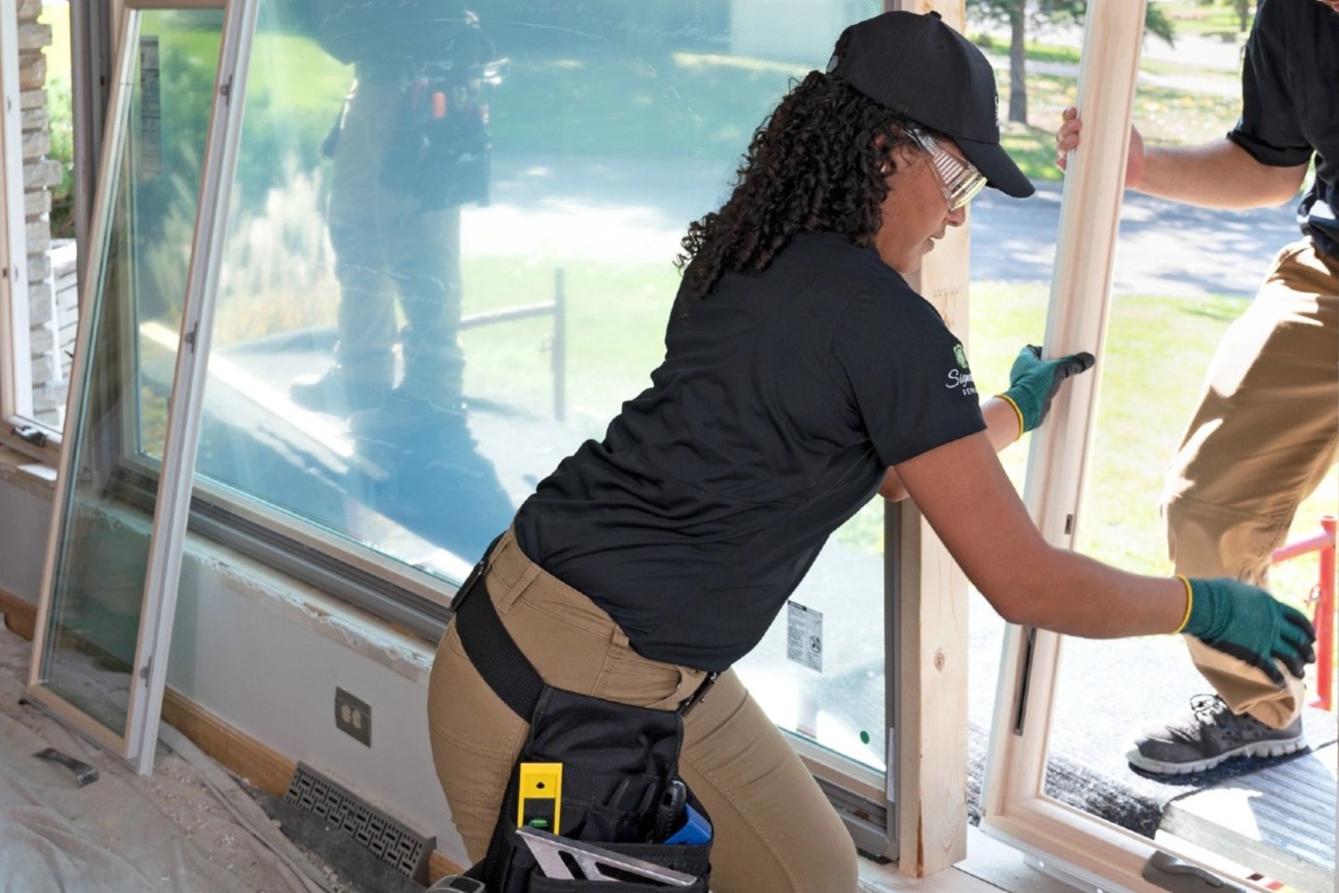 Certified master installers handling a large picture window in the installation process.