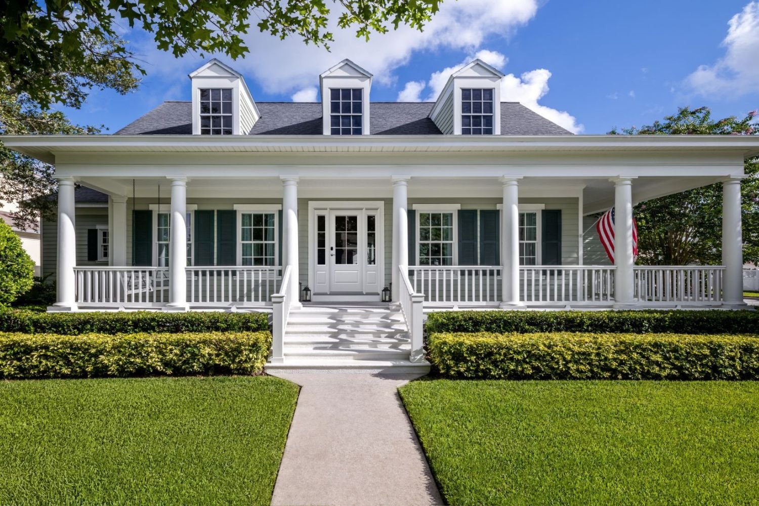 Front exterior of a classic residential home featuring Renewal by Andersen replacement windows with grille patterns, highlighting enhanced natural light, energy efficiency, and enduring style.
