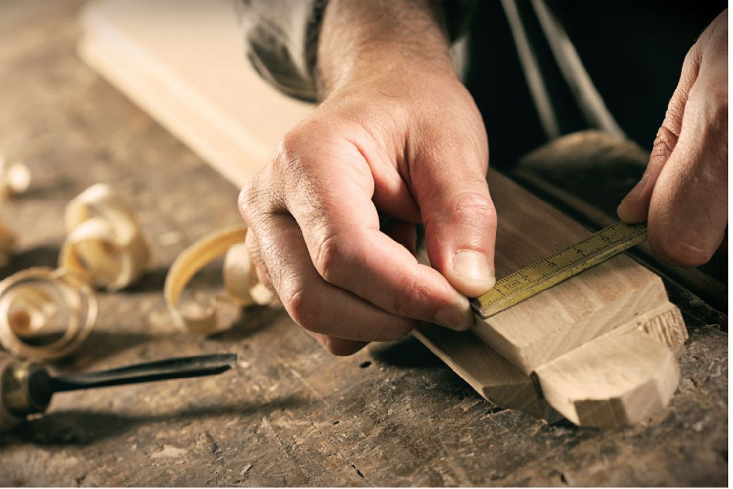 Close up of a set of hands carving a wood corner weld for a window.