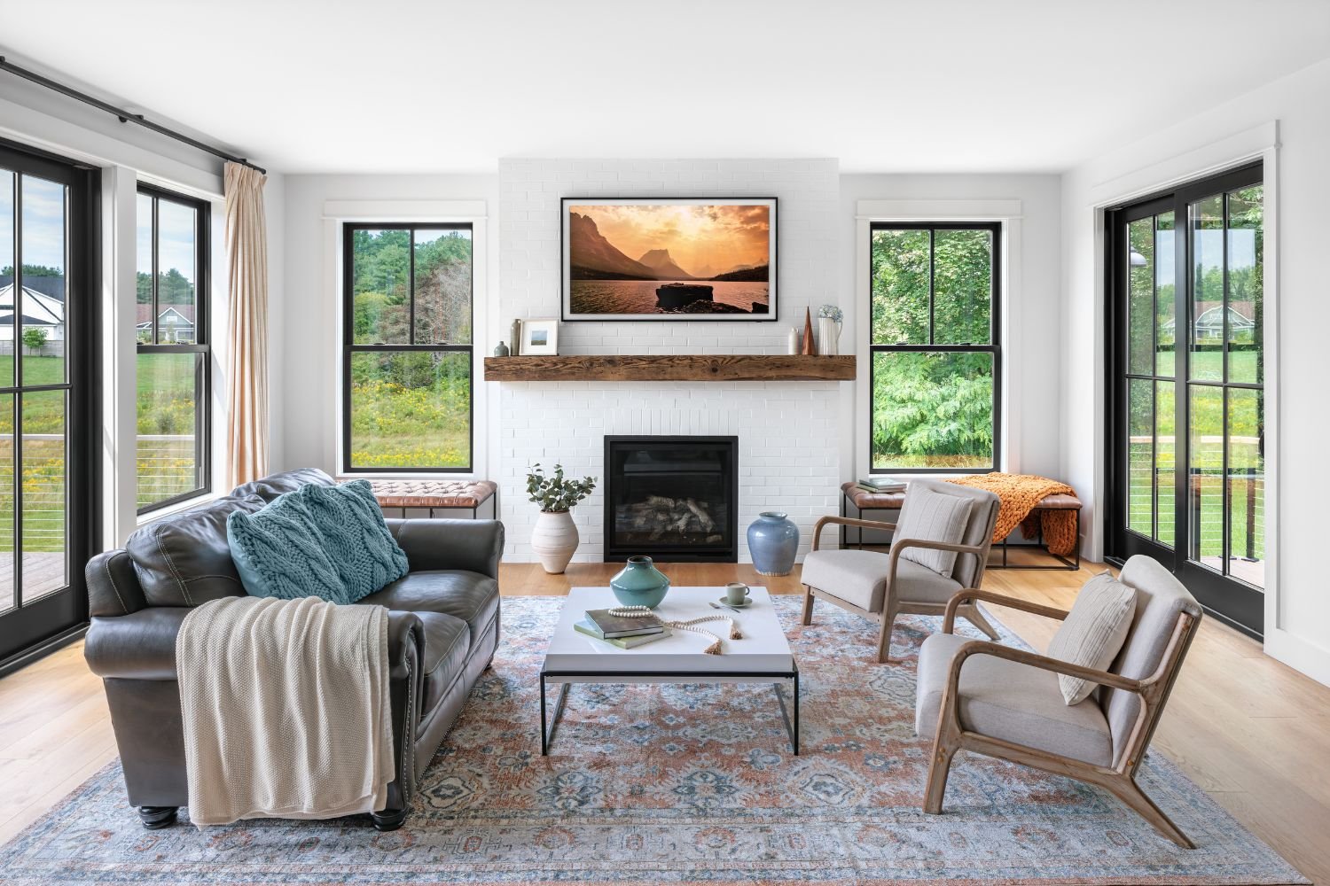 A white living room with wood floors and windows on all sides.