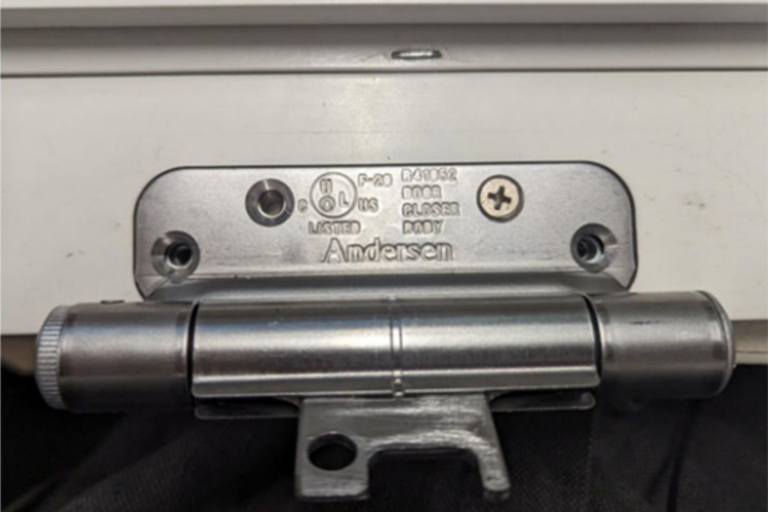 Up close example of a silver Renewal by Andersen UL Certified Class 1 self-closing door hinge mounted on a white door.