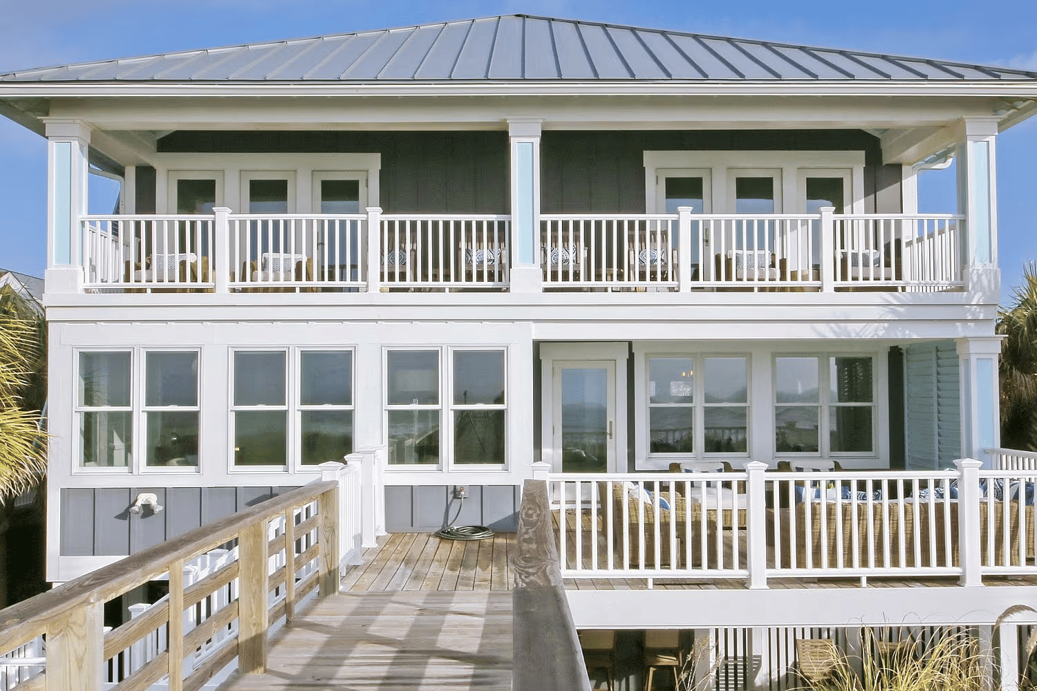 Rear view of a two story gray beach home with Renewal by Andersen Acclaim Impact windows.