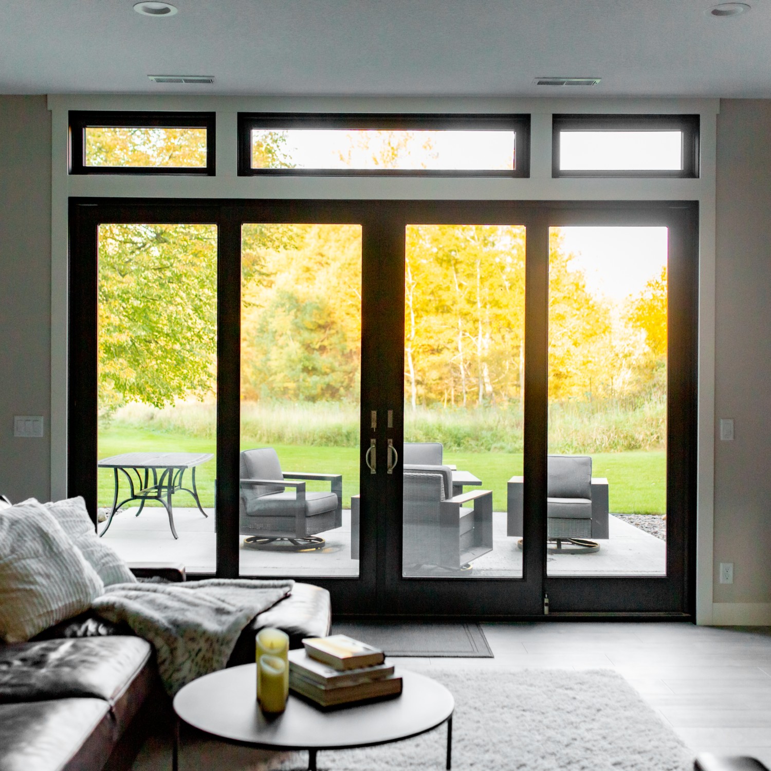 Black sliding glass doors. Two sets of doors with transom windows looking out over a patio.