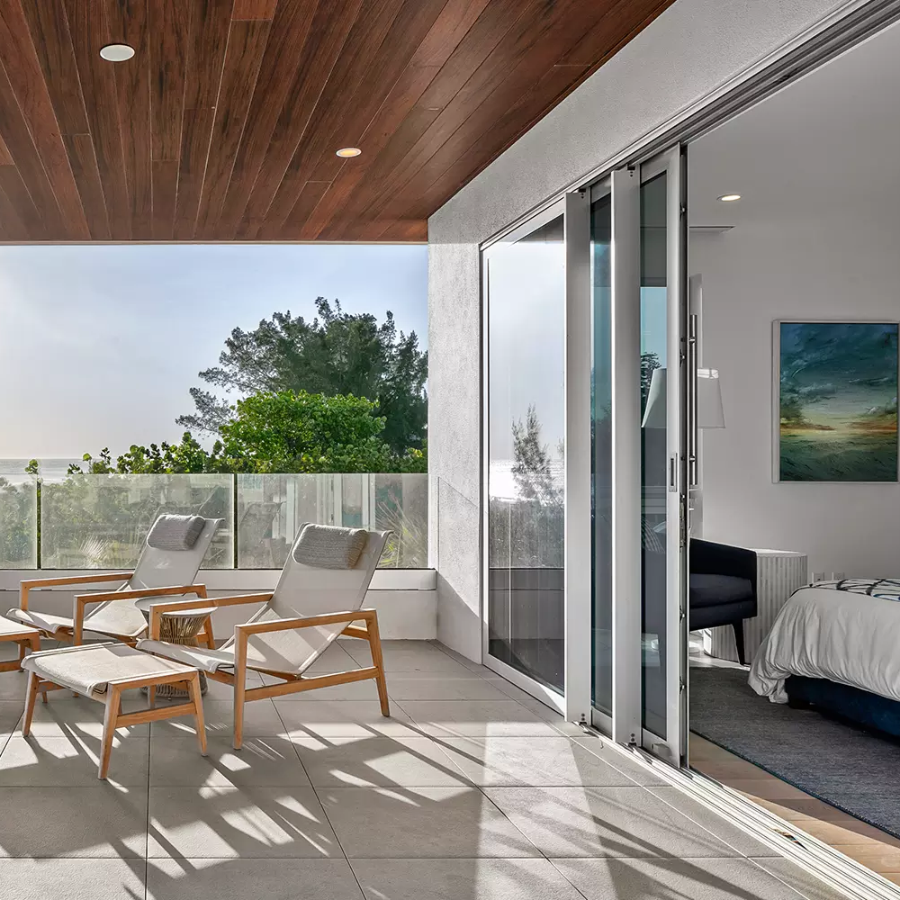 A lanai of a home with a beach view and a multipanel sliding door.