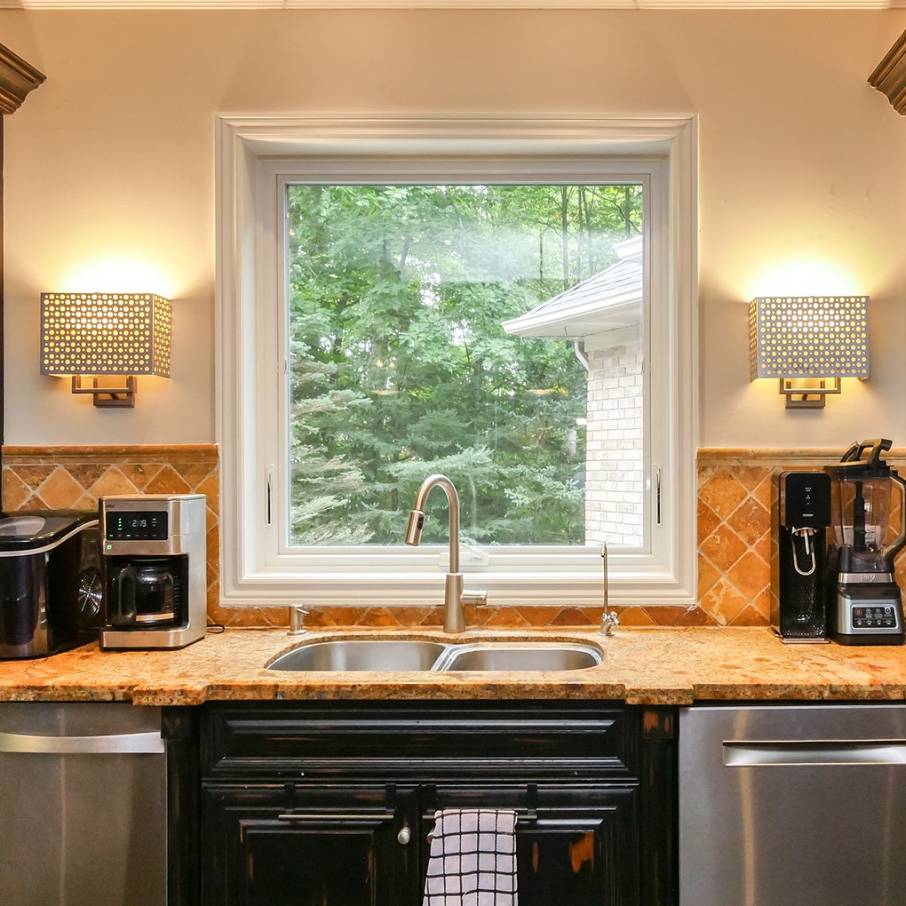A white awning window above a sink with granite counters.