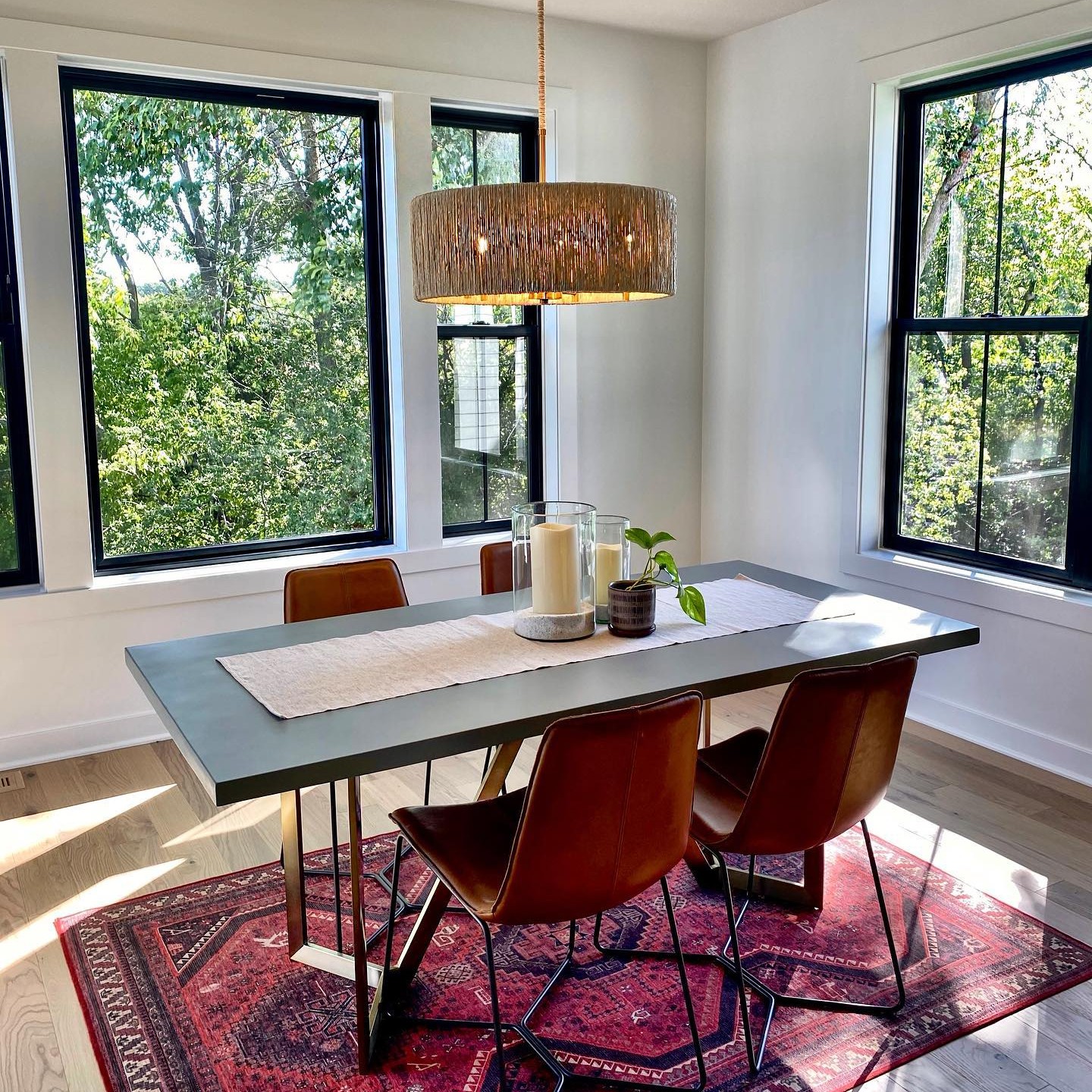 A dining room with a red rug. There is a large picture window behind the table.