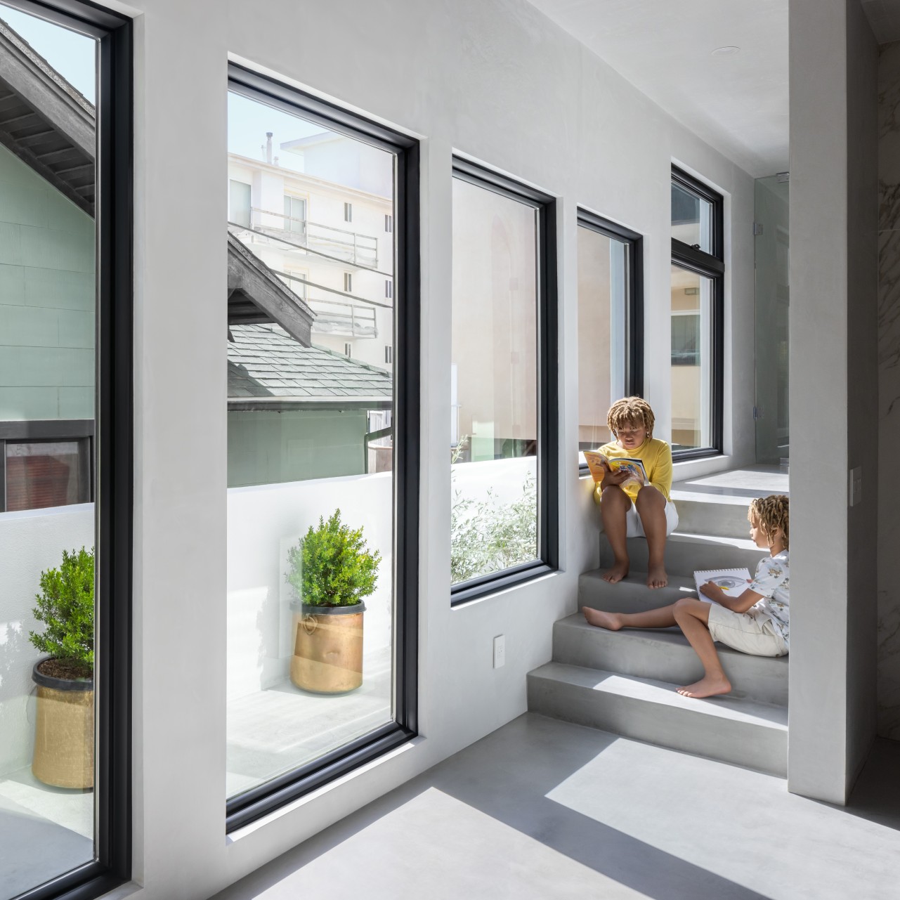 Breegan Jane's hallway. Two boys sitting on a step in front of one of several large picture windows.