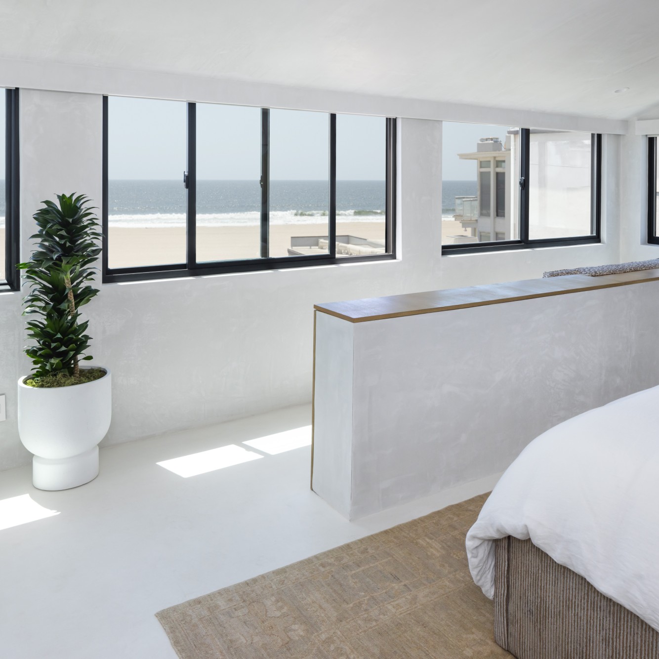 A bank of sliding, or gliding, windows in a bedroom overlooking the beach.